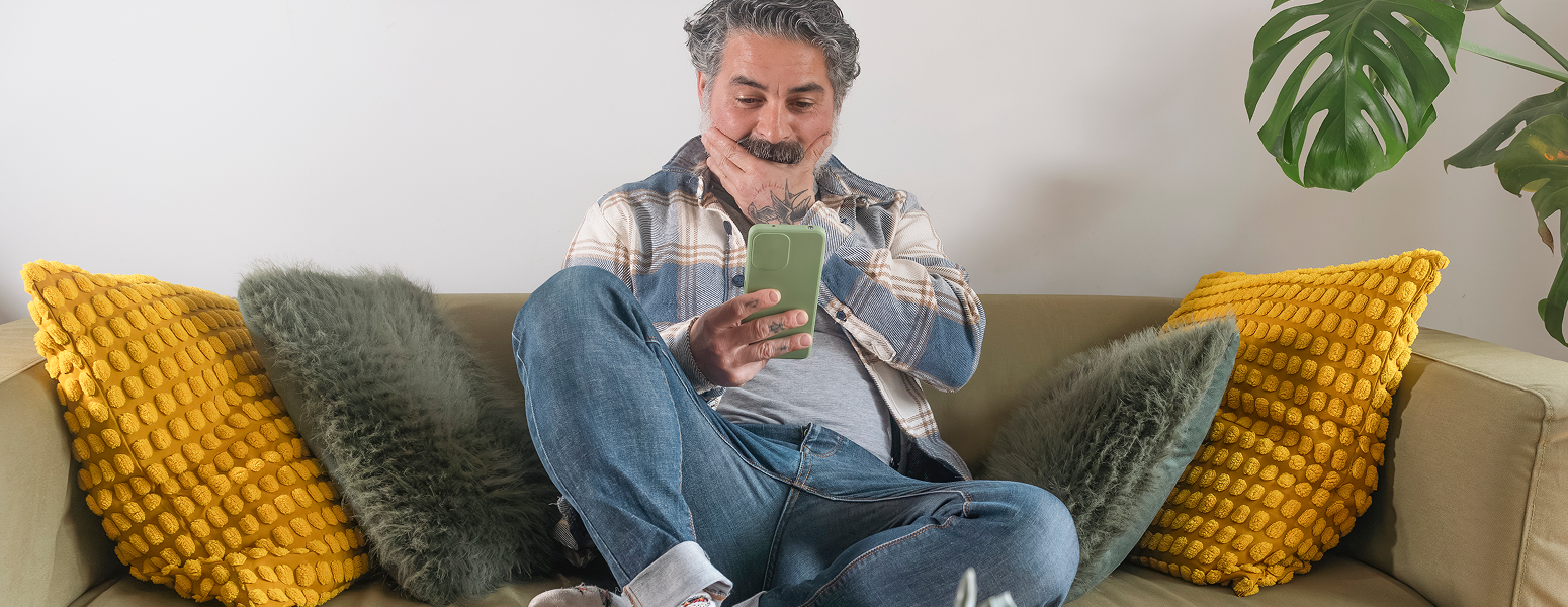 man looking at his phone sitting on a sofa