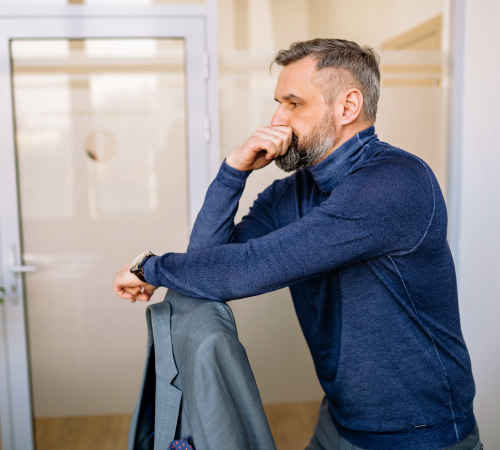 Man looking thoughtful leaning on the back of a chair