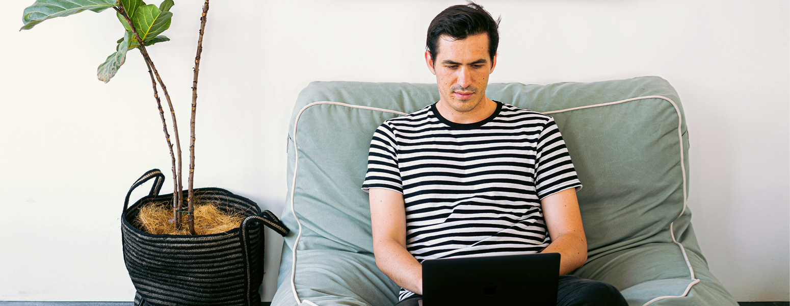 A man in a striped t-shirt sitting on a comfy chair