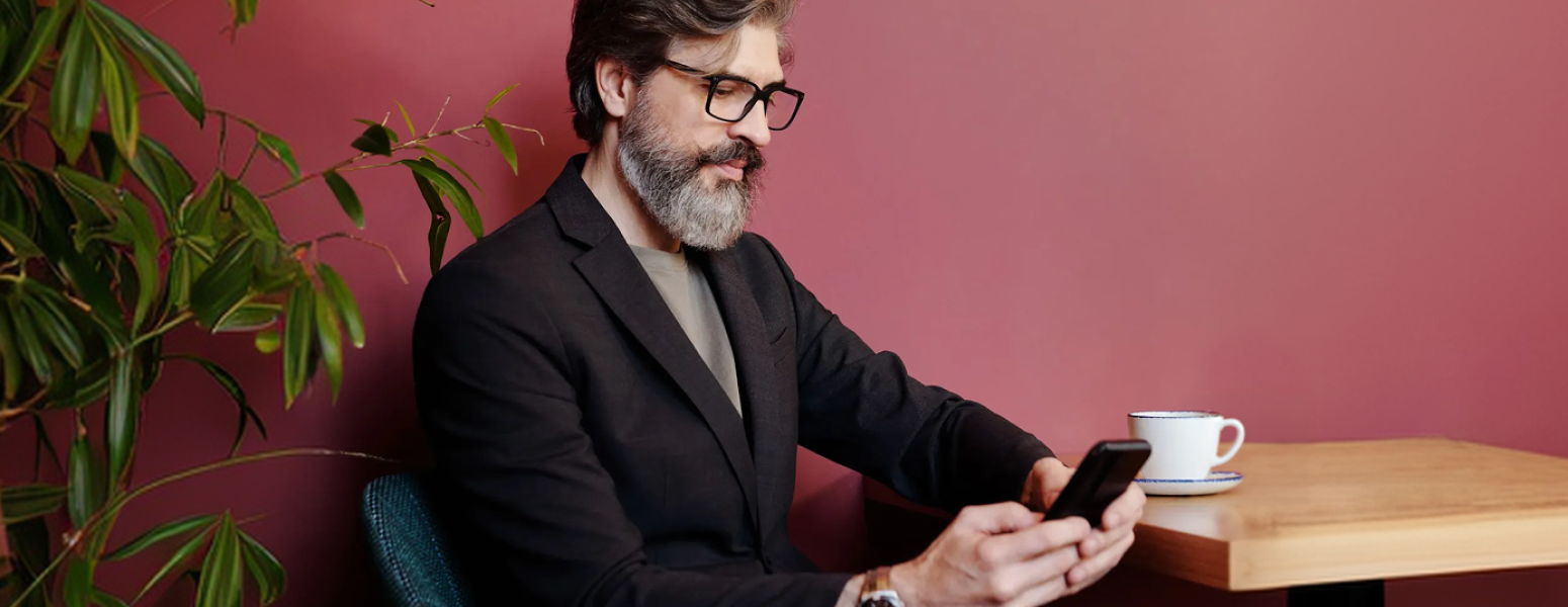 A man drinking coffee and scrolling on his phone
