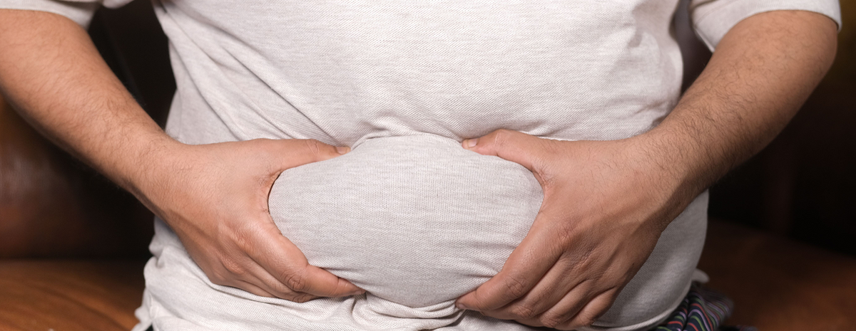A man squeezing his belly fat